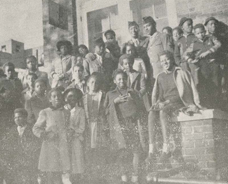 Image depicting a large group of Black children gathered around a stone staircase