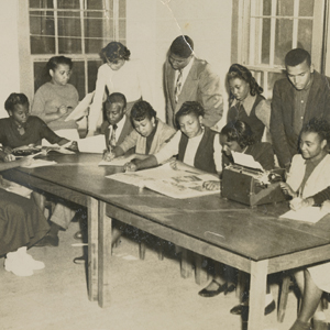 Image of students working at a large desk in a classroom